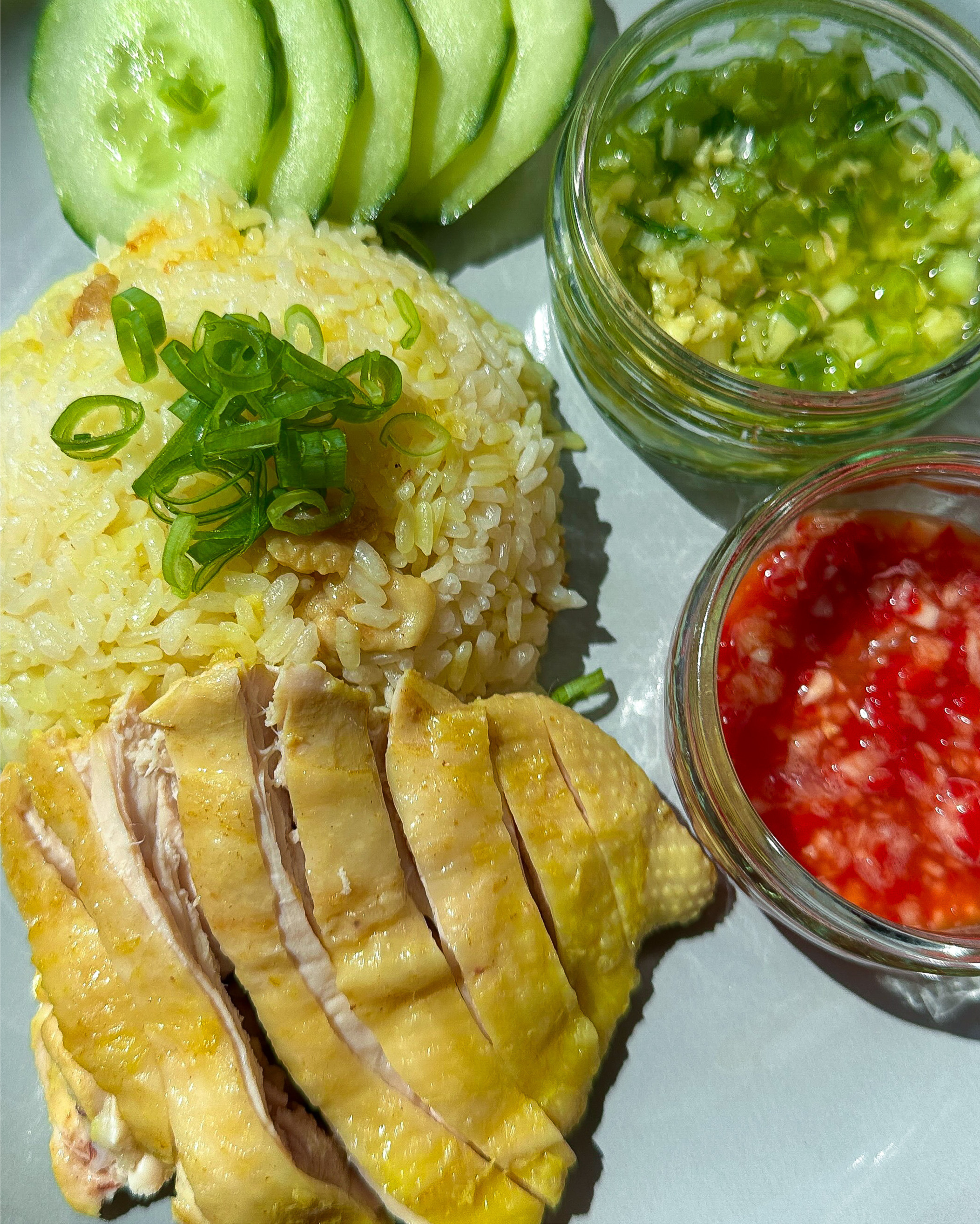 singapore hainanese chicken rice with rice, cucumber, ginger scallion oil, chilli garlic sauce