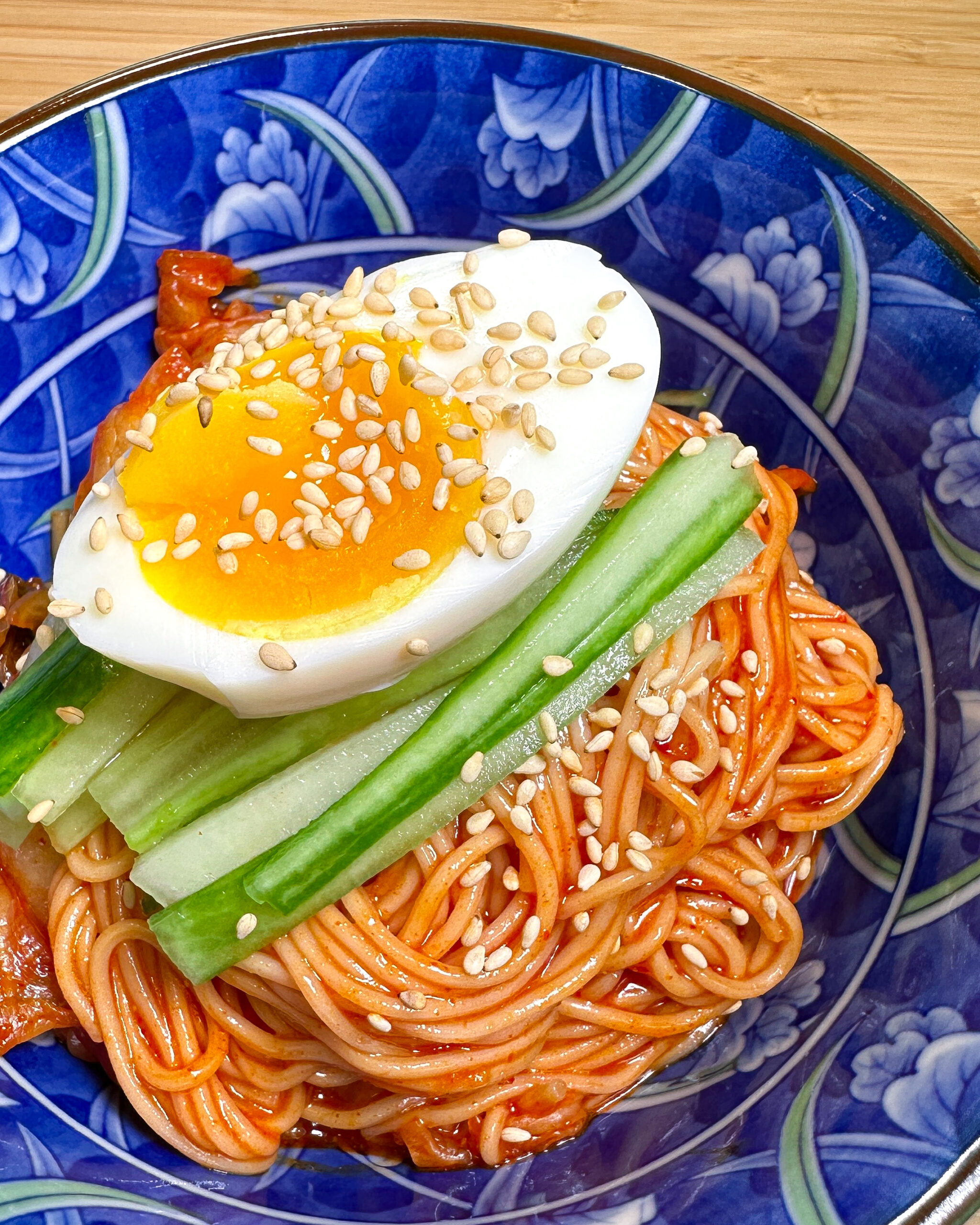 korean cold spicy noodles with cucumber, boiled egg and sesame seeds